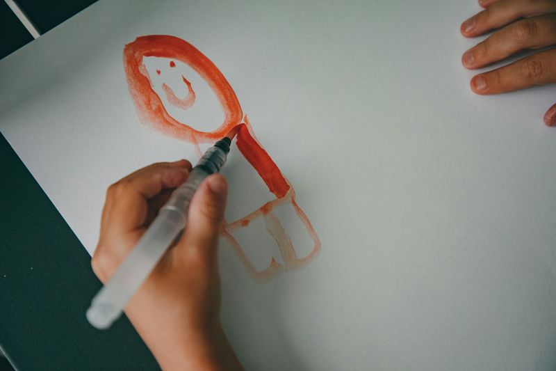 Kind malt eine Zeichnung mit rotem Stift